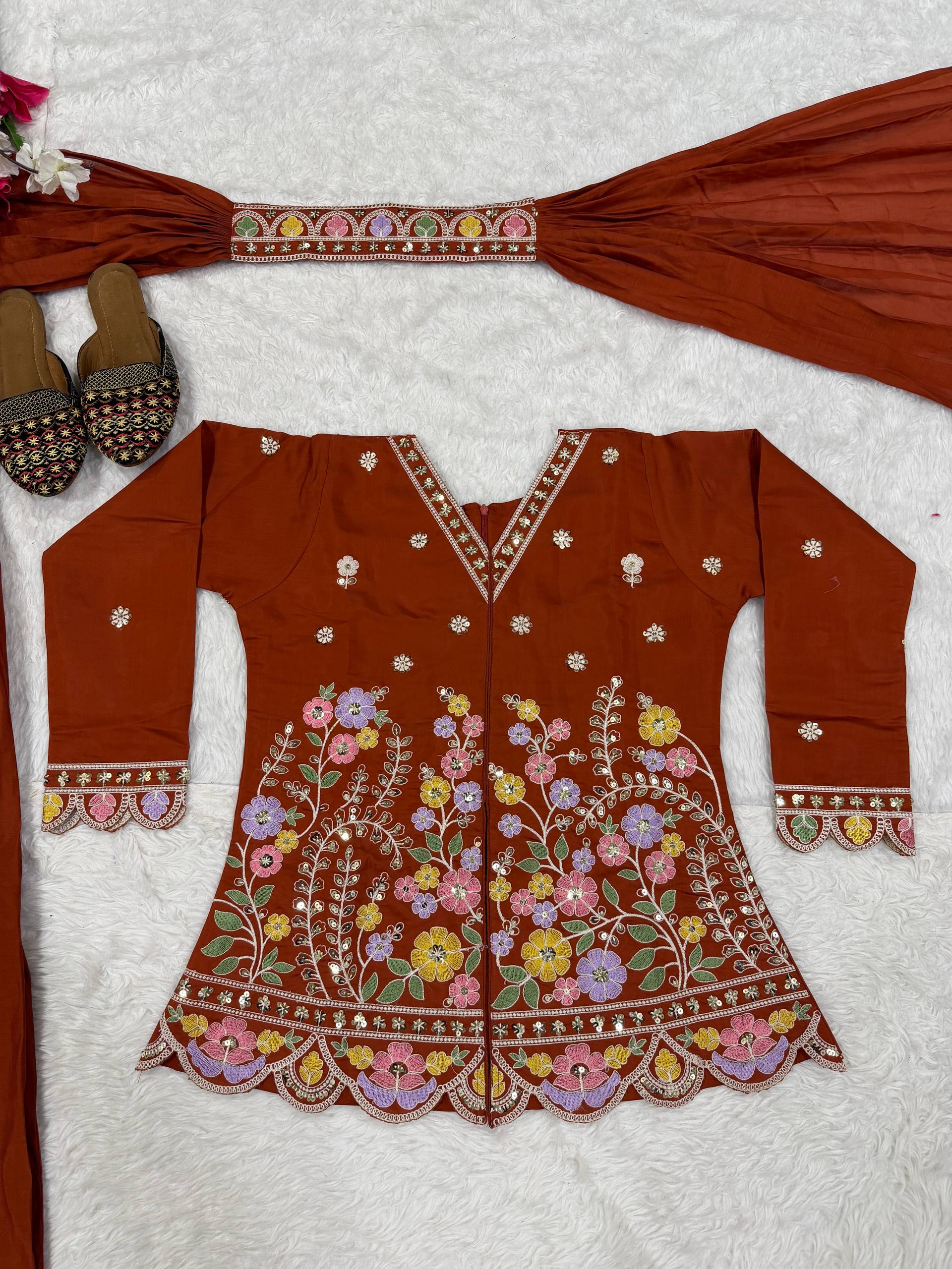 Resplendent Rust Orange Peplum Kurti and Flared Palazzo Suit Set Adorned with Intricate Multicolored Floral Embroidery, Sequin Accents, and Ornate Scalloped Borders